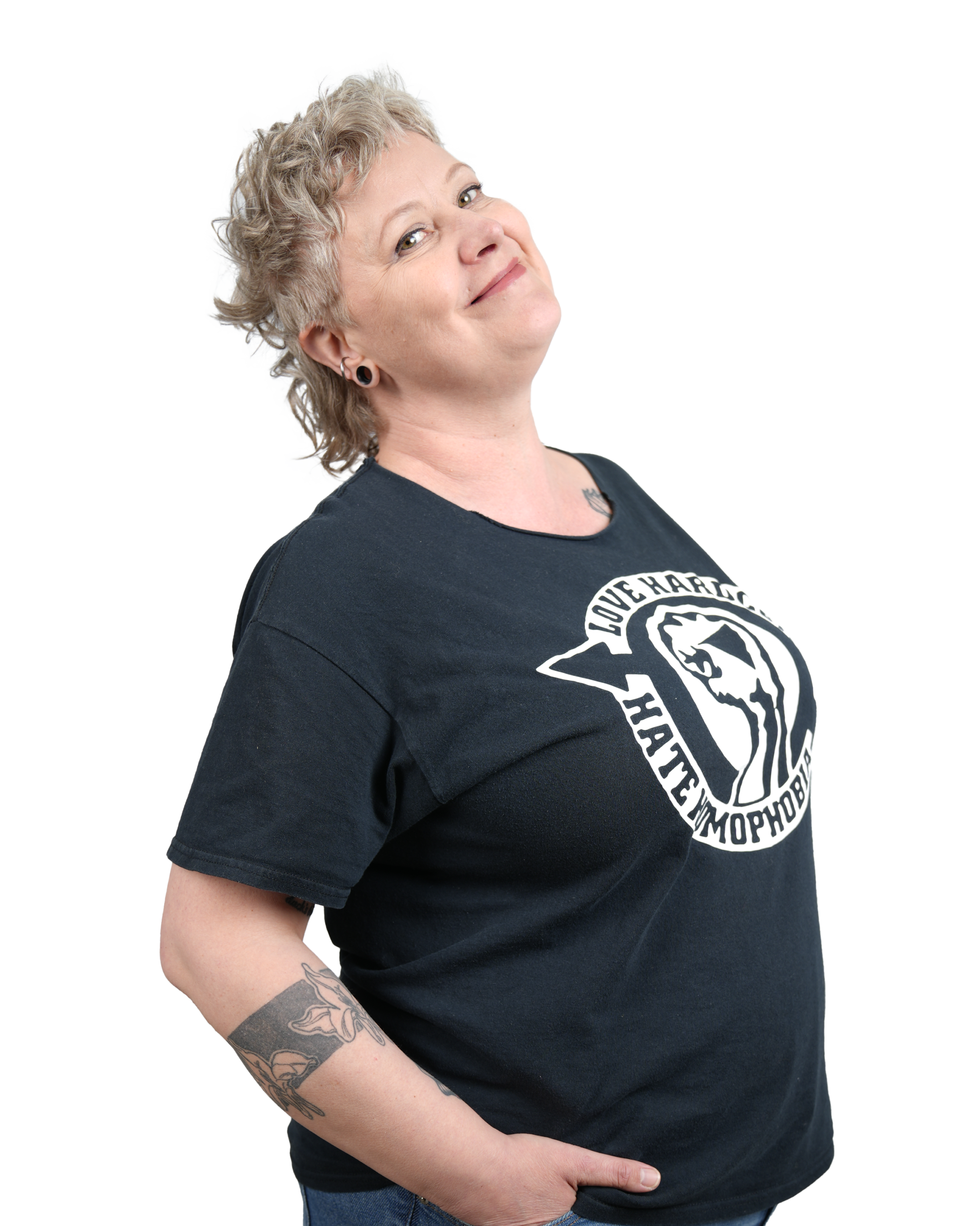 Raisa mustassa t-paidassa, kädet taskuissa, hymyilee 